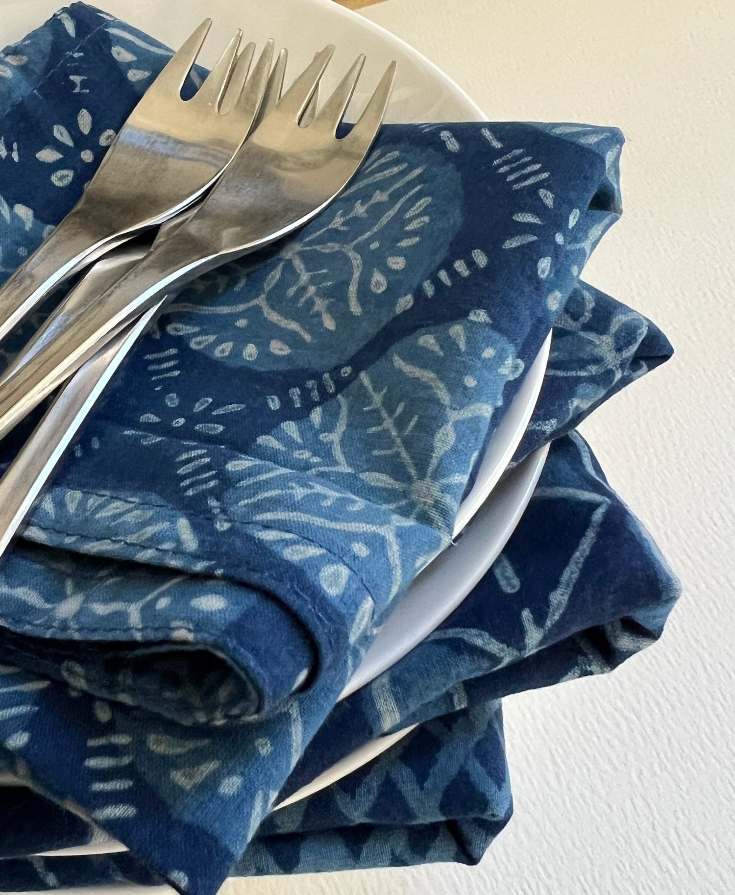 Stack of plates with indigo table napkins and cutlery